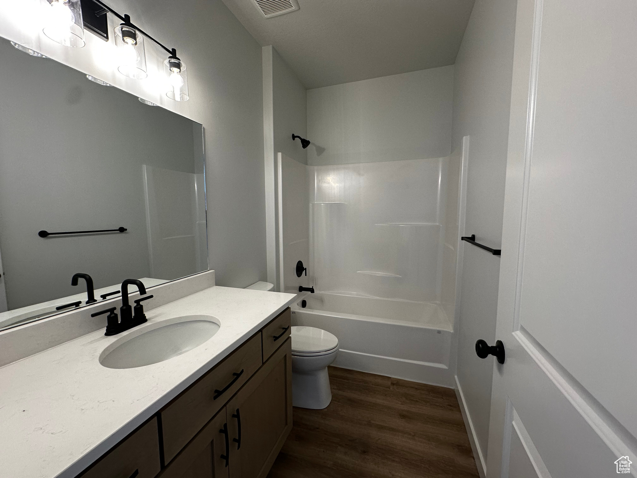 Full bathroom featuring wood-type flooring, toilet, vanity, and bathing tub / shower combination