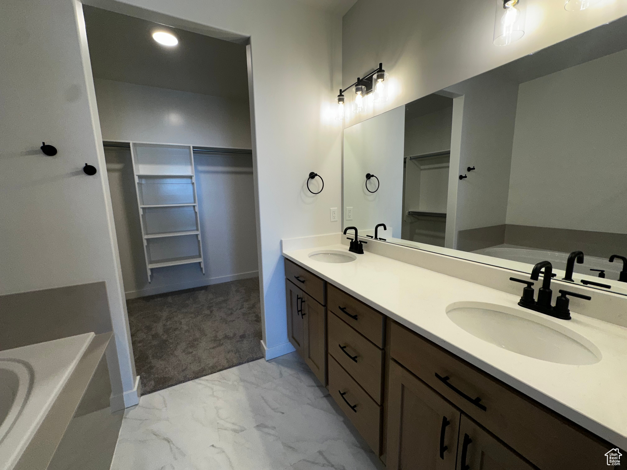 Bathroom with tile floors, dual vanity, and a washtub