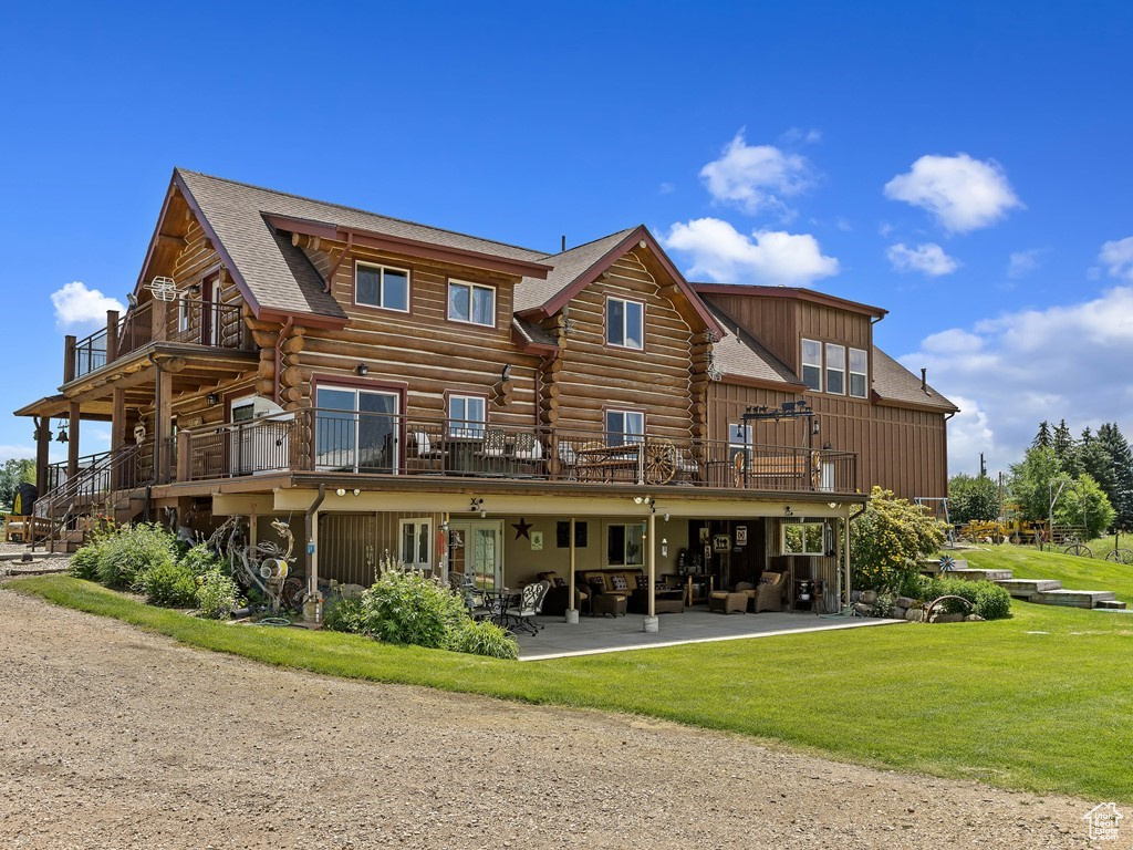 Back of property with a lawn, a deck, a balcony, and a patio