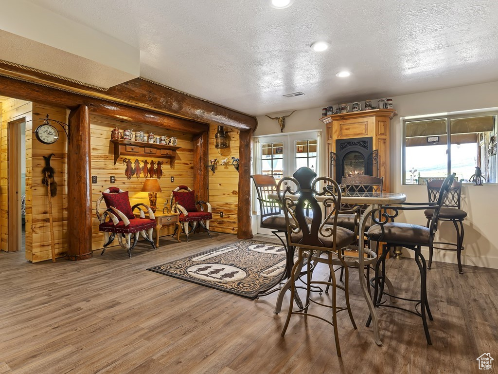 Dining area with french doors, wood walls, a textured ceiling, and dark hardwood / wood-style floors