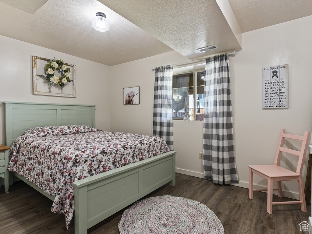 Bedroom featuring a textured ceiling and dark hardwood / wood-style floors