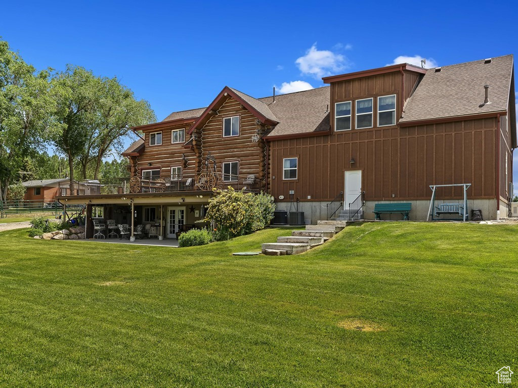 Back of house with a lawn and a patio