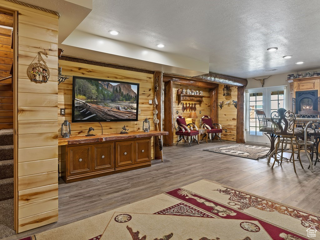 Interior space with french doors, a textured ceiling, bar area, light wood-type flooring, and wood walls