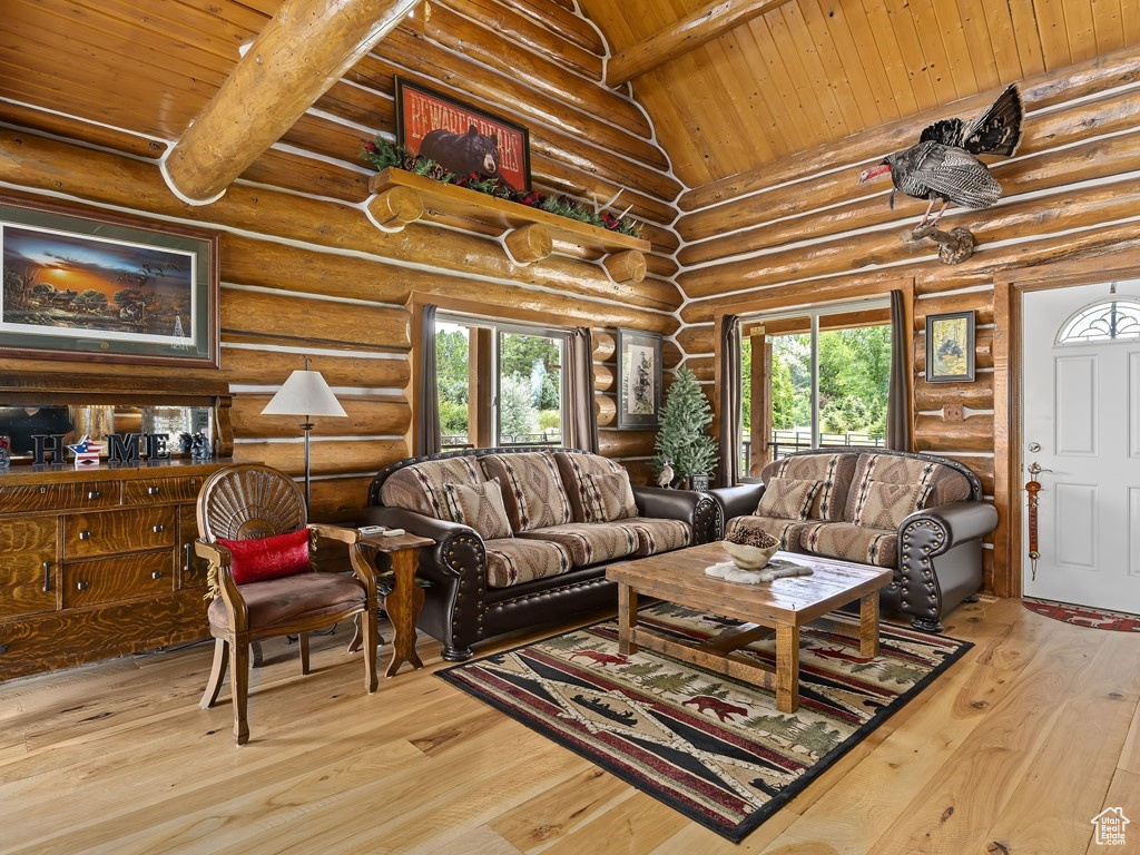 Living room featuring light hardwood / wood-style flooring, wood ceiling, rustic walls, and a healthy amount of sunlight