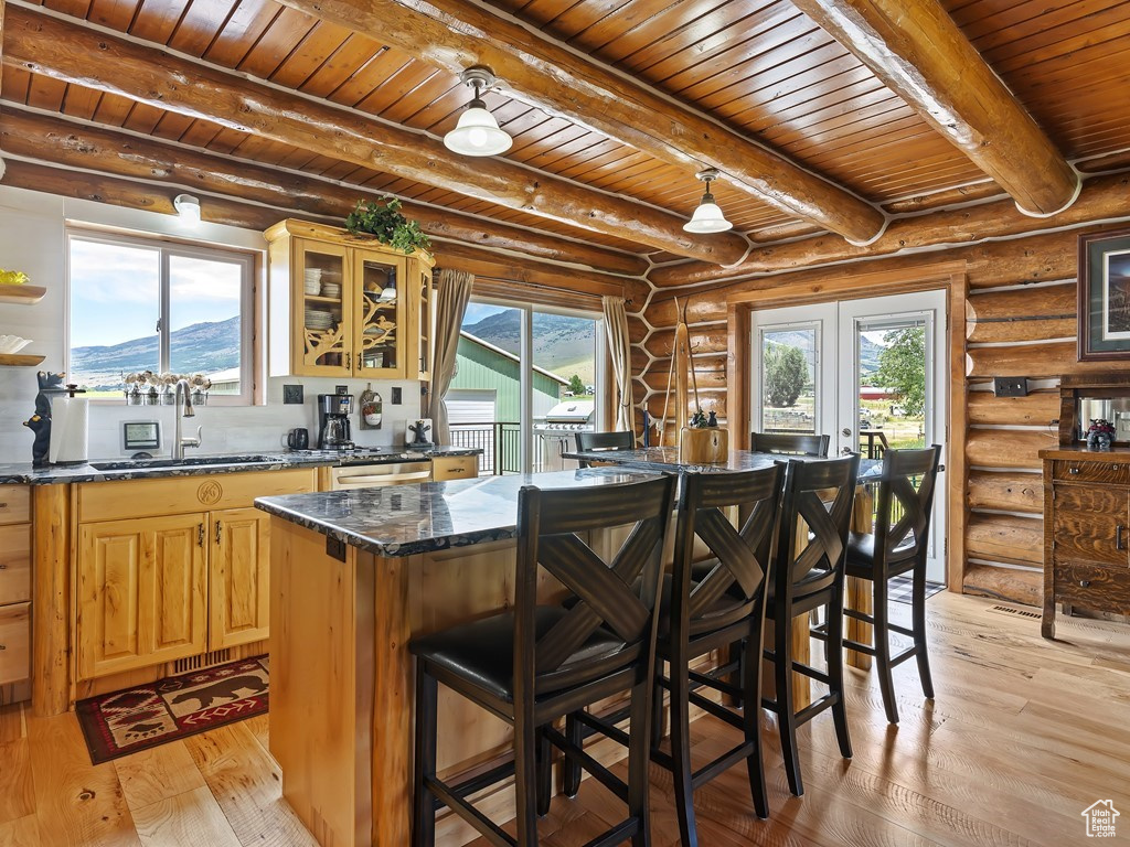 Kitchen featuring beamed ceiling, light wood-type flooring, and log walls