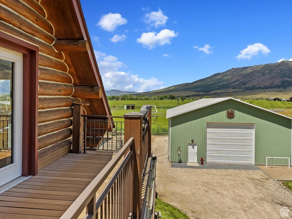 Wooden deck with an outdoor structure, a garage, and a mountain view