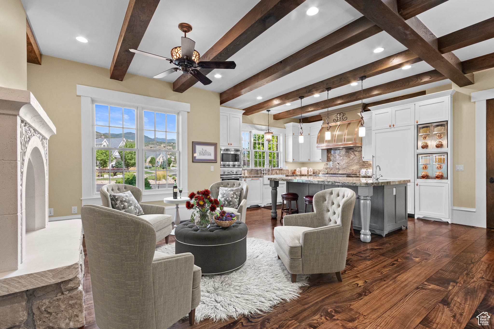 Living room with dark wood-type flooring, beamed ceiling, and ceiling fan