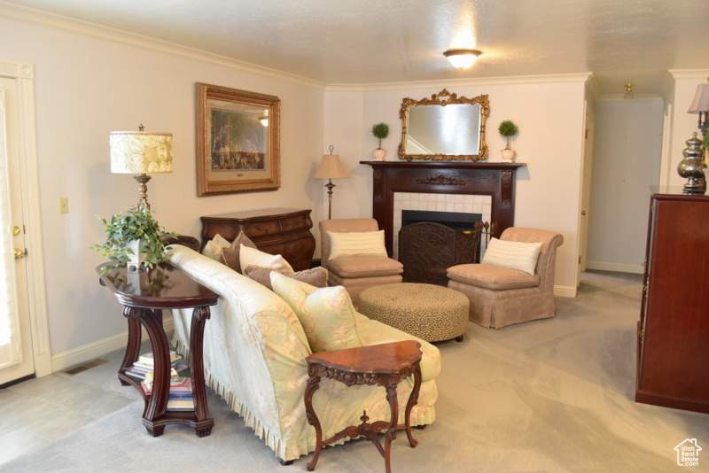 Living room with crown molding, a tile fireplace, and light colored carpet