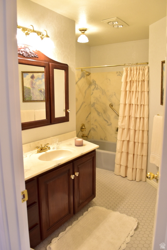 Bathroom featuring shower / bath combination with curtain, vanity, and tile floors