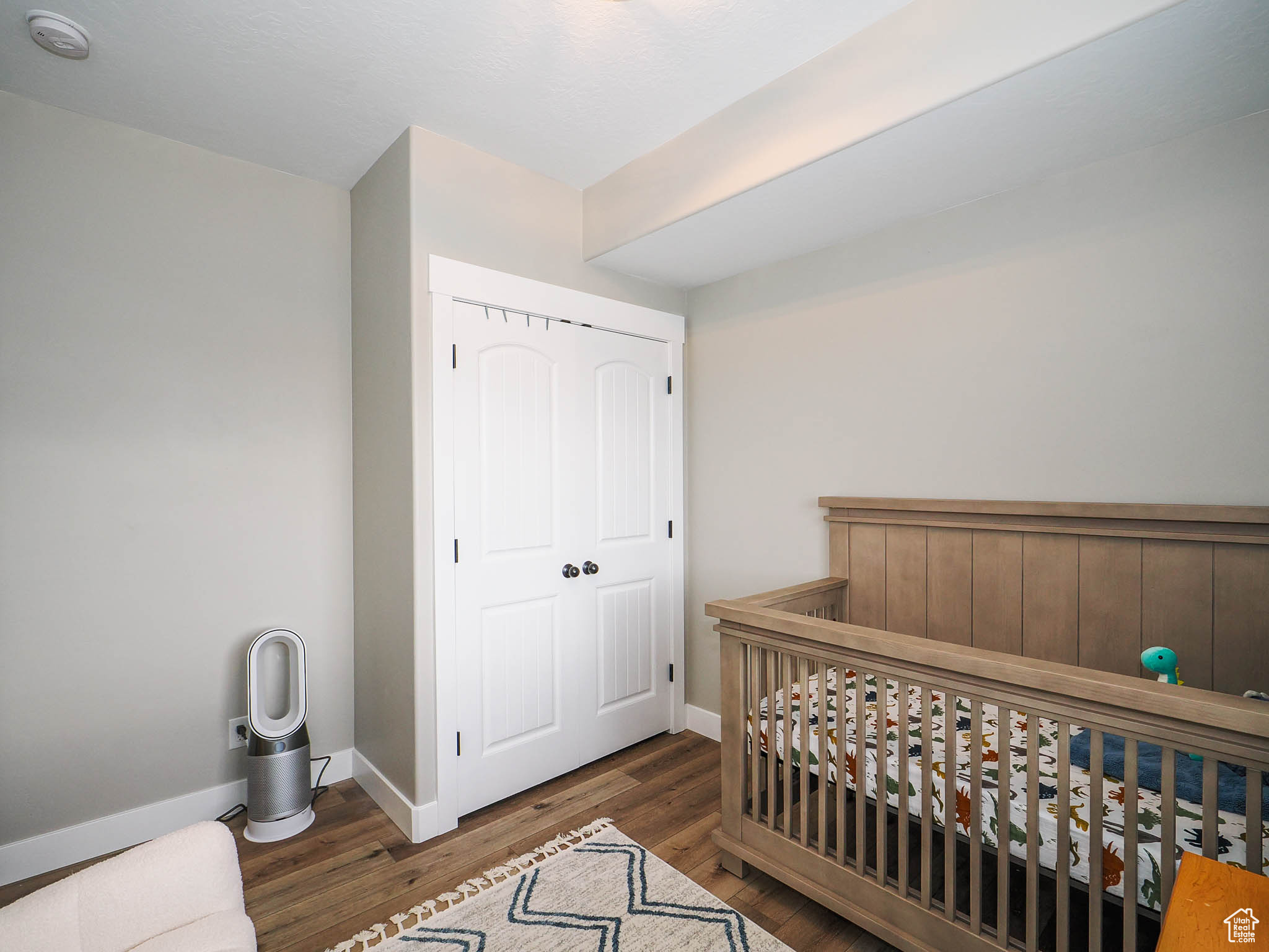 Bedroom with dark hardwood / wood-style flooring, a crib, and a closet