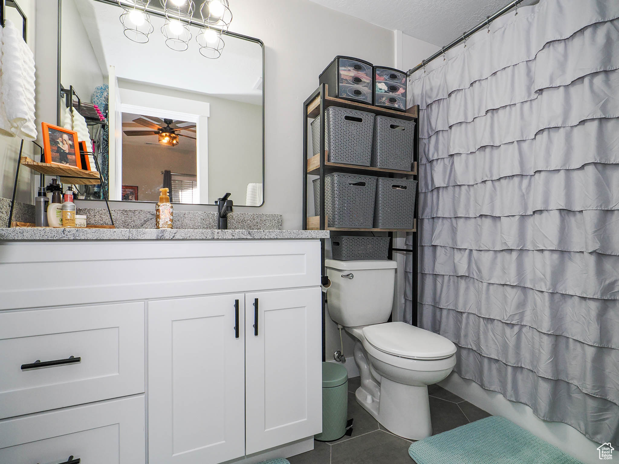 Bathroom featuring toilet, large vanity, tile flooring, and ceiling fan