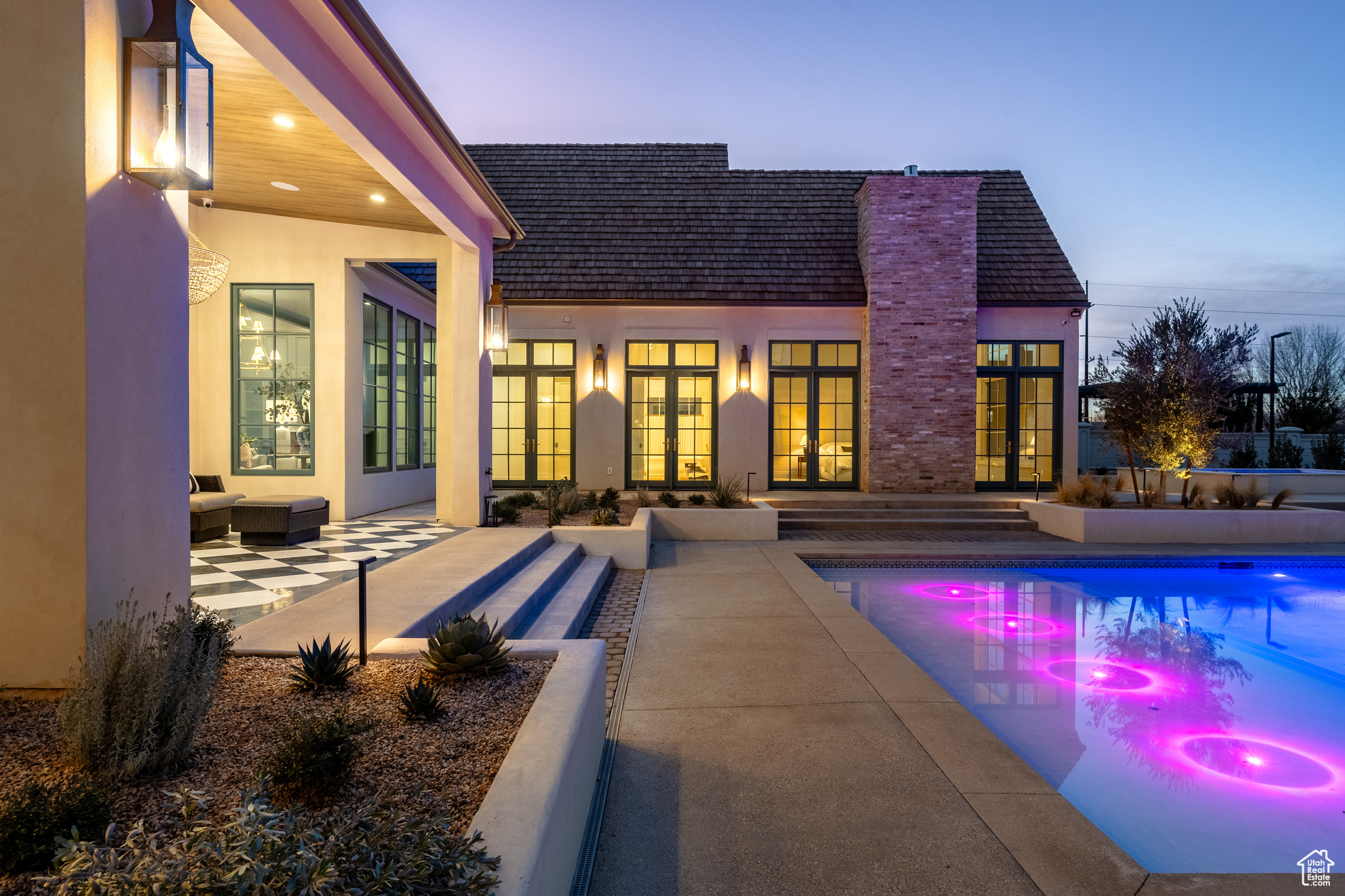 Pool at dusk with a patio and french doors