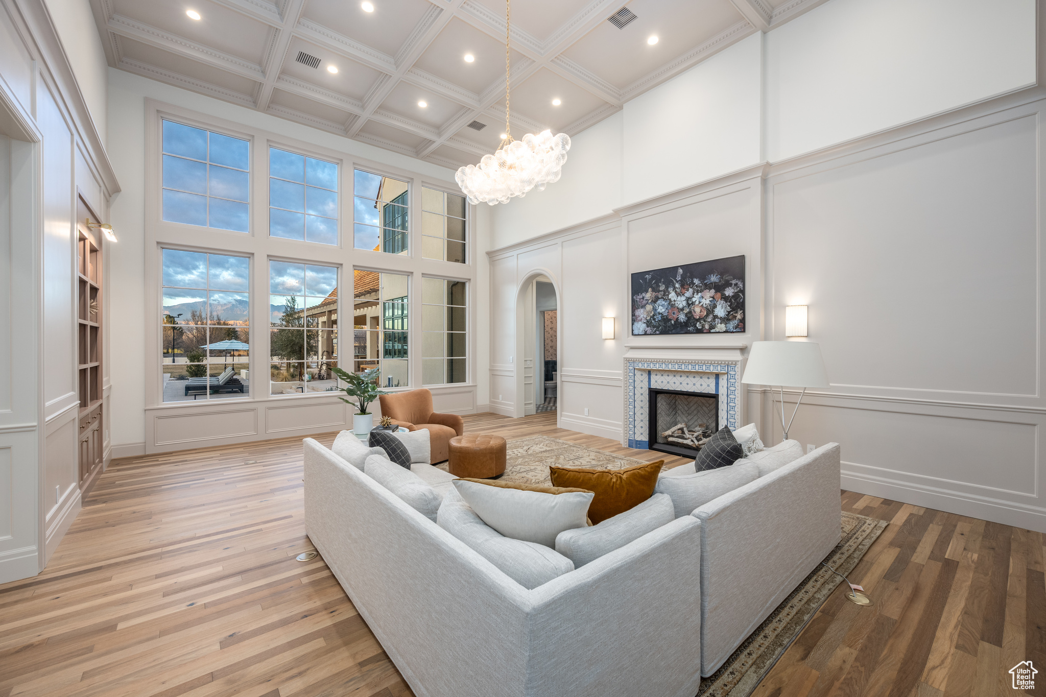 Living room featuring an inviting chandelier, light hardwood / wood-style floors, a high ceiling, beam ceiling, and coffered ceiling