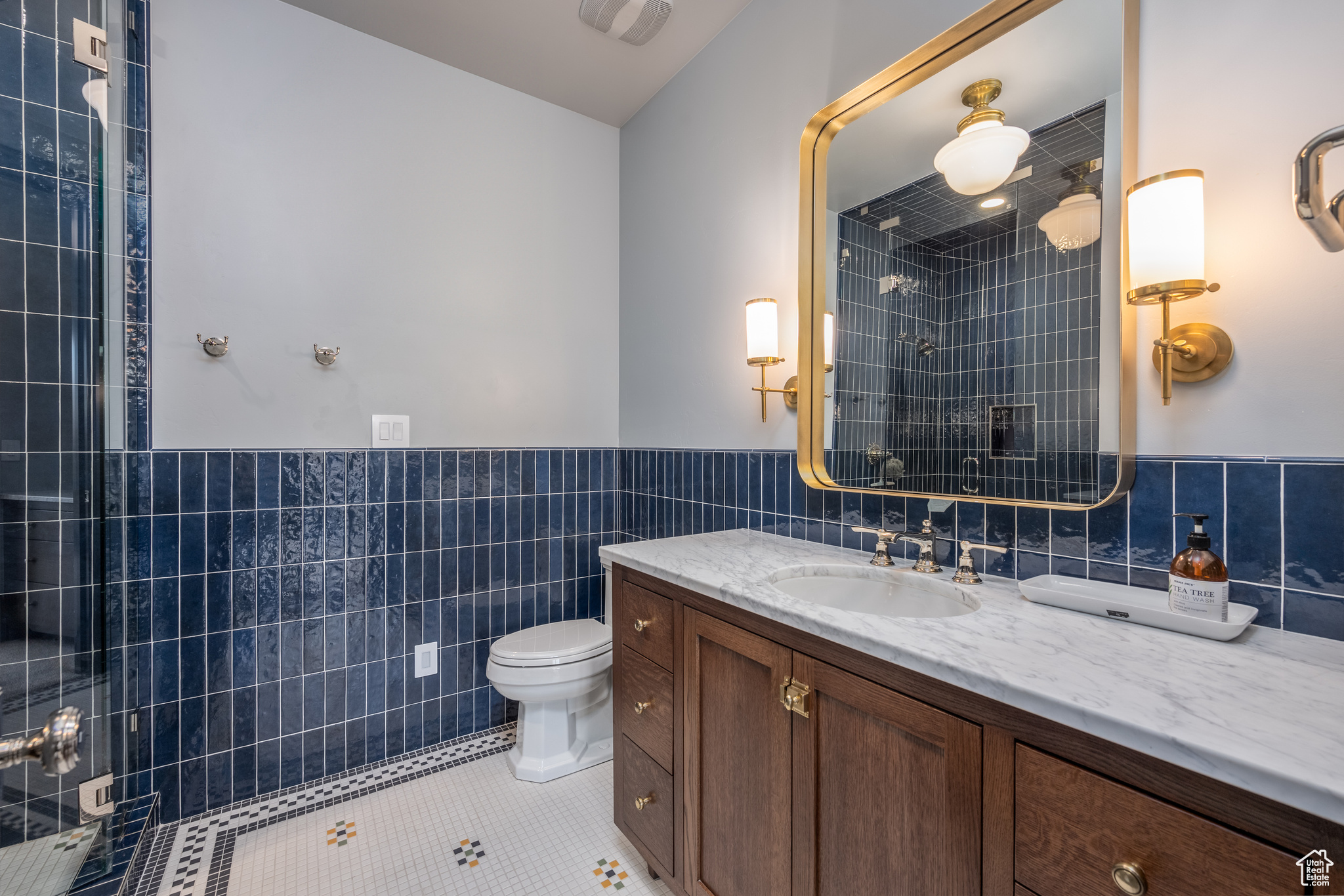 Bathroom with tasteful backsplash, toilet, vanity, and tile walls