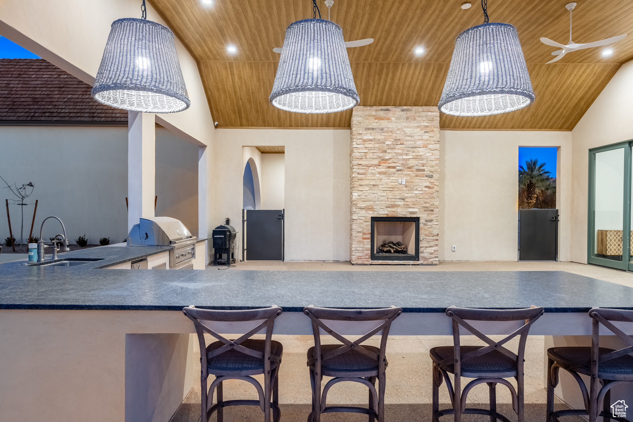 Kitchen featuring decorative light fixtures, a breakfast bar, a stone fireplace, wood ceiling, and high vaulted ceiling
