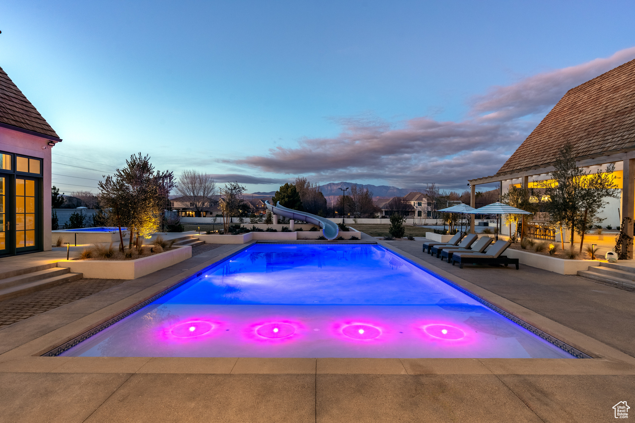 Pool at dusk featuring a water slide and a patio area