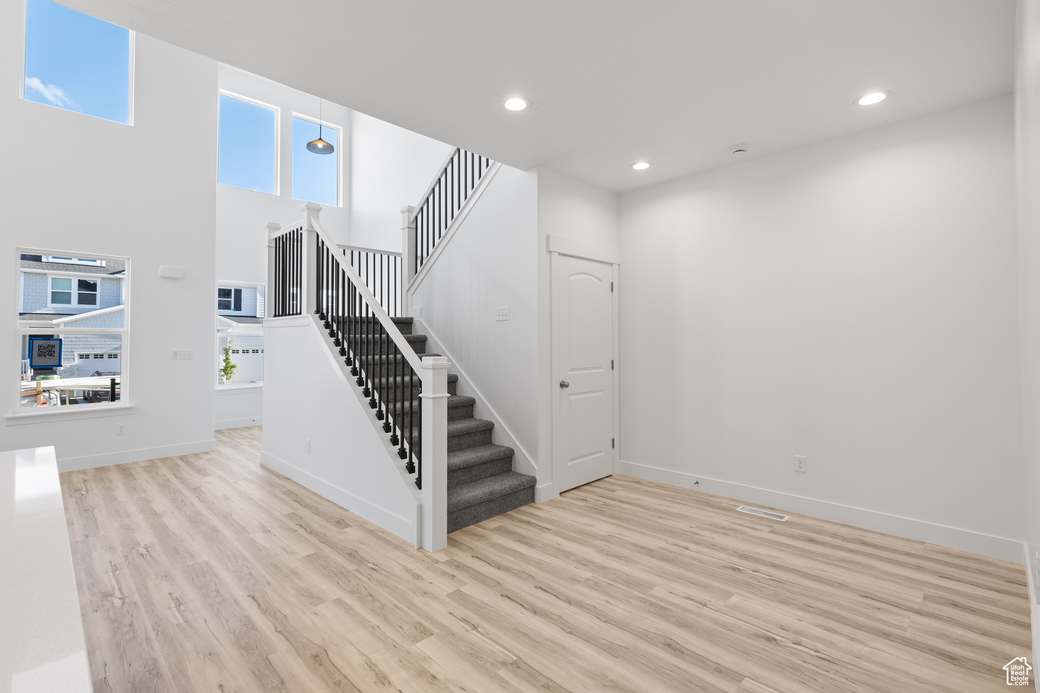 Stairs featuring a towering ceiling and light hardwood / wood-style flooring