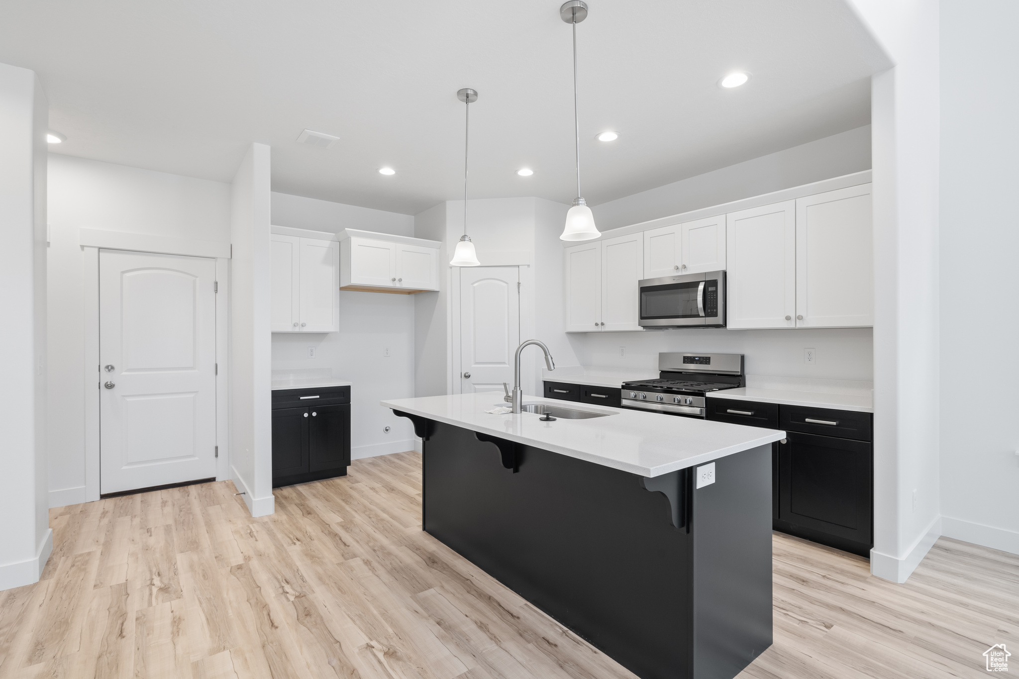 Kitchen with an island with sink, sink, light hardwood / wood-style flooring, and stainless steel appliances