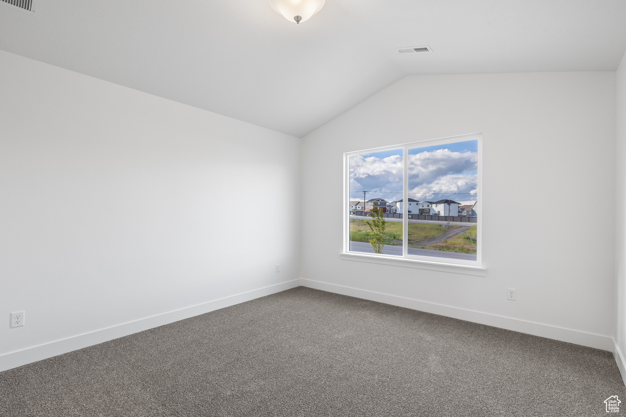 Unfurnished room with dark carpet and lofted ceiling