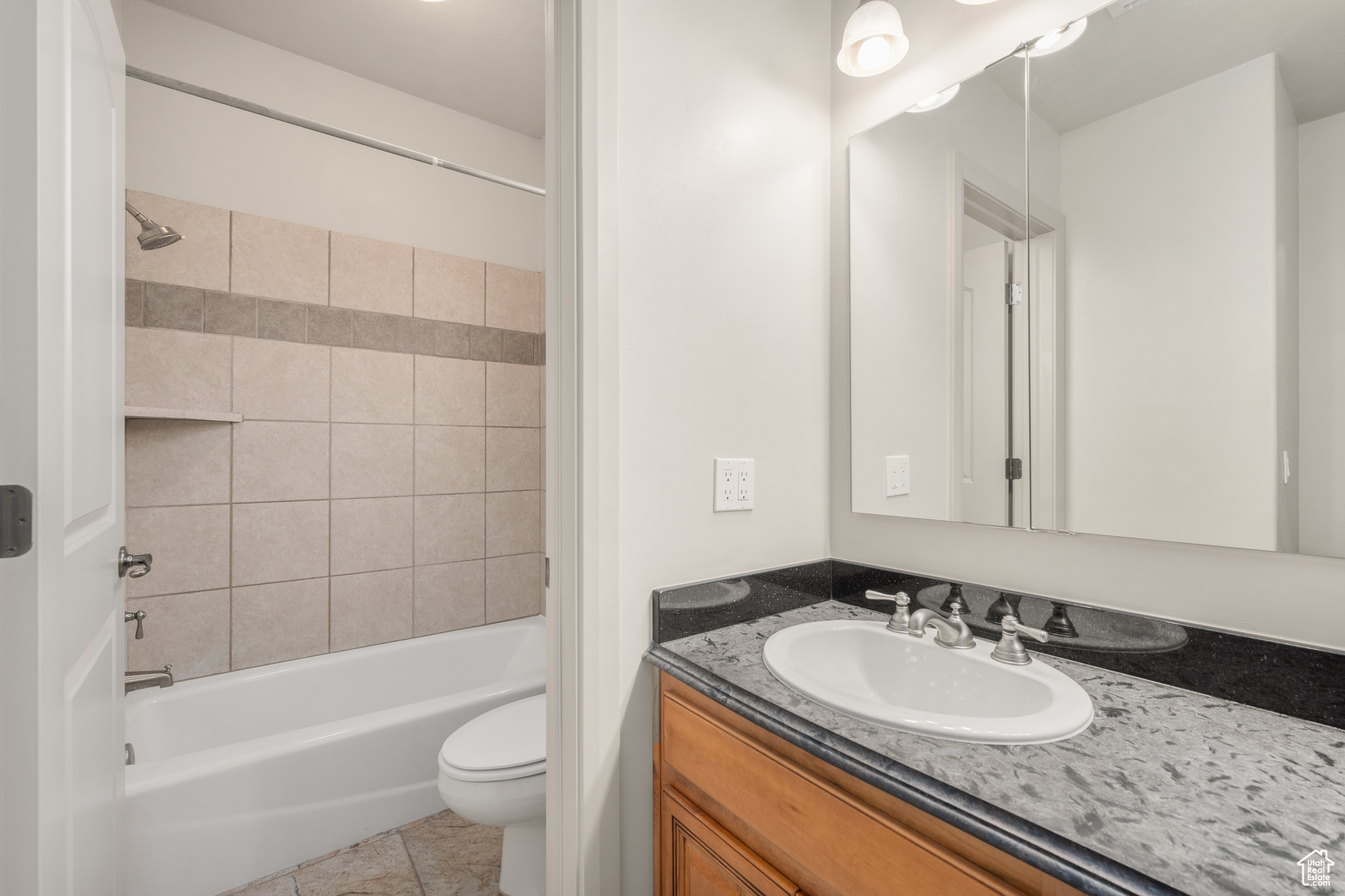 Full bathroom featuring tile floors, tiled shower / bath, oversized vanity, and toilet