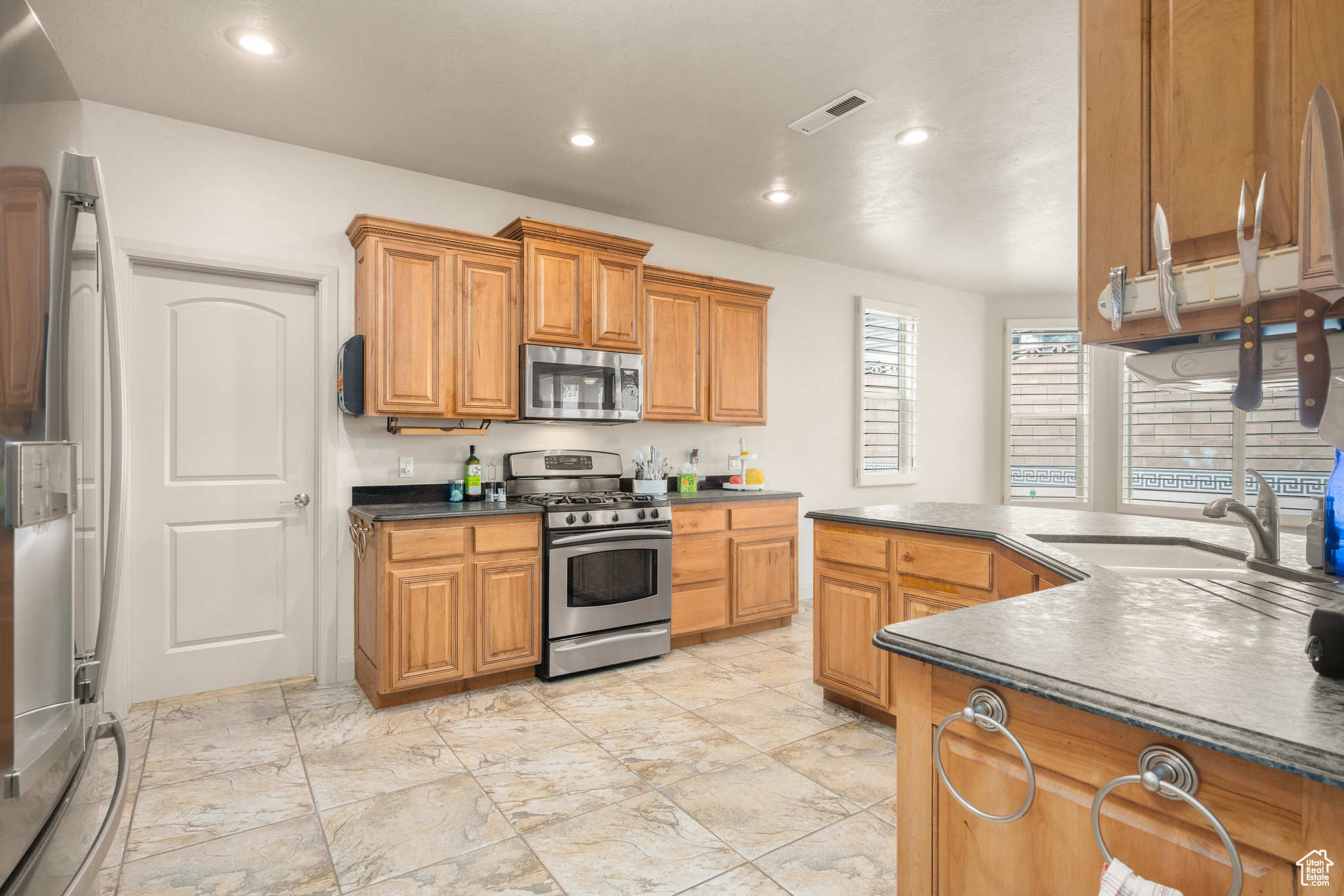 Kitchen featuring sink, light tile flooring, and appliances with stainless steel finishes