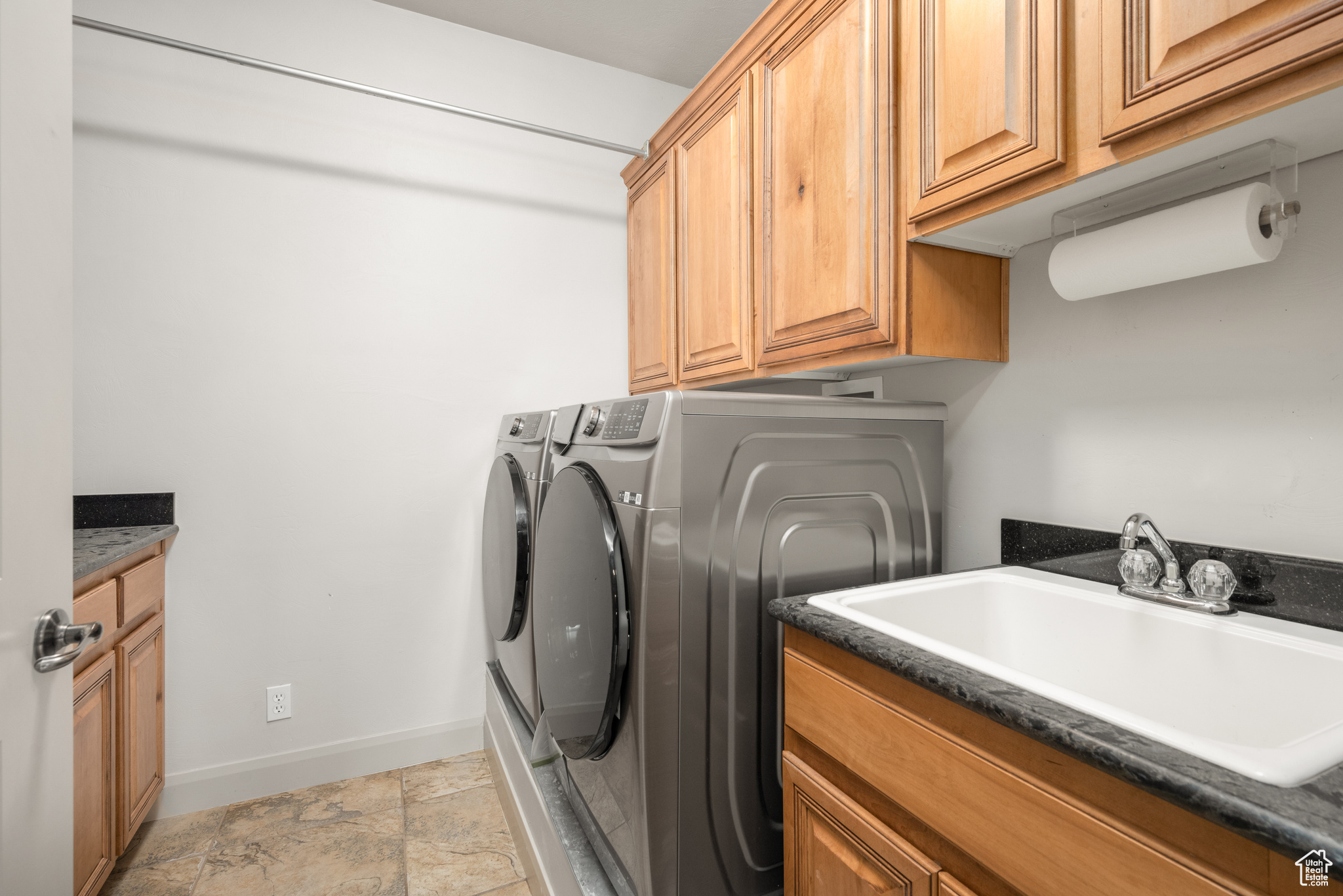 Washroom featuring washing machine and clothes dryer, cabinets, sink, and light tile floors