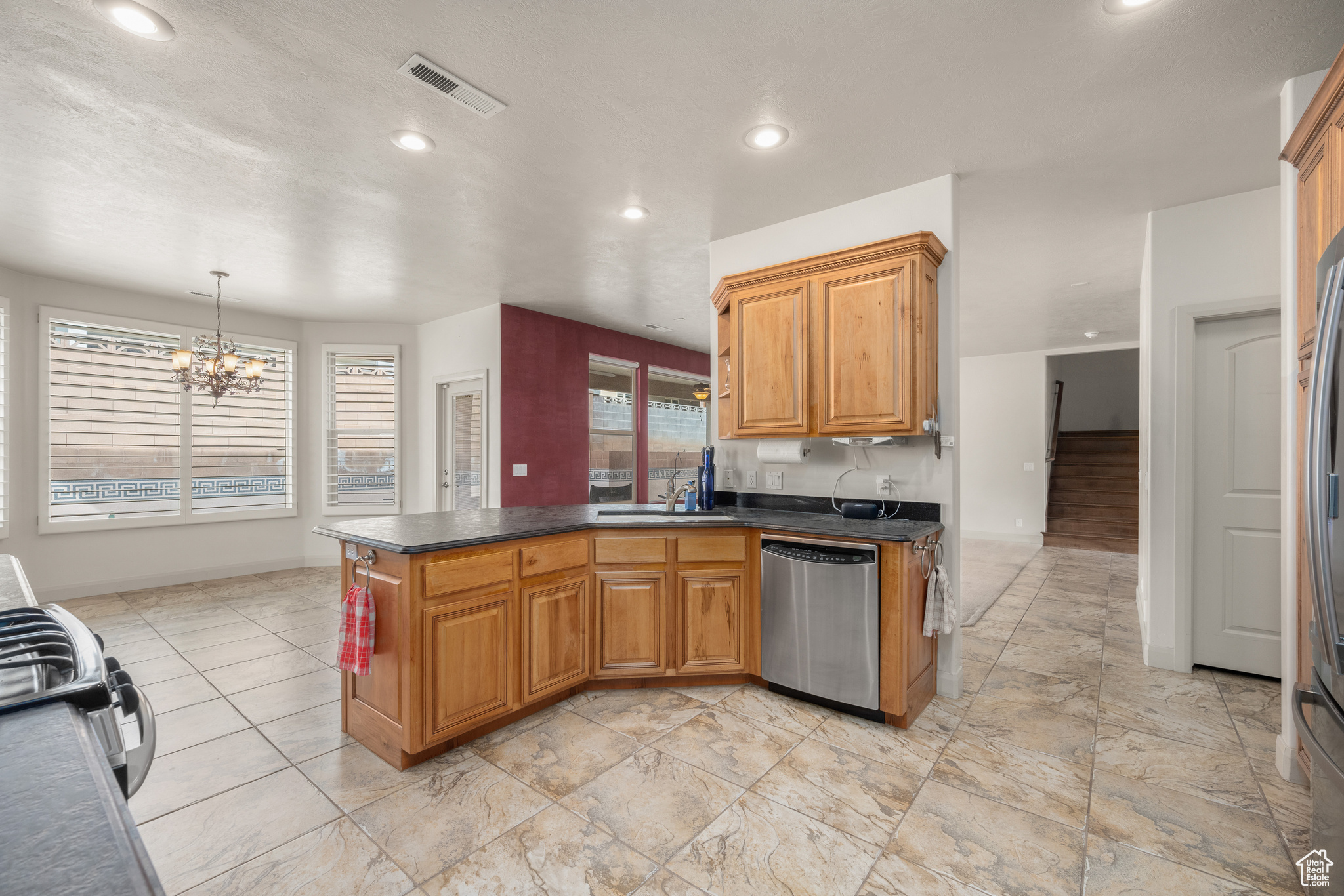 Kitchen with light tile flooring, an inviting chandelier, stove, hanging light fixtures, and dishwasher