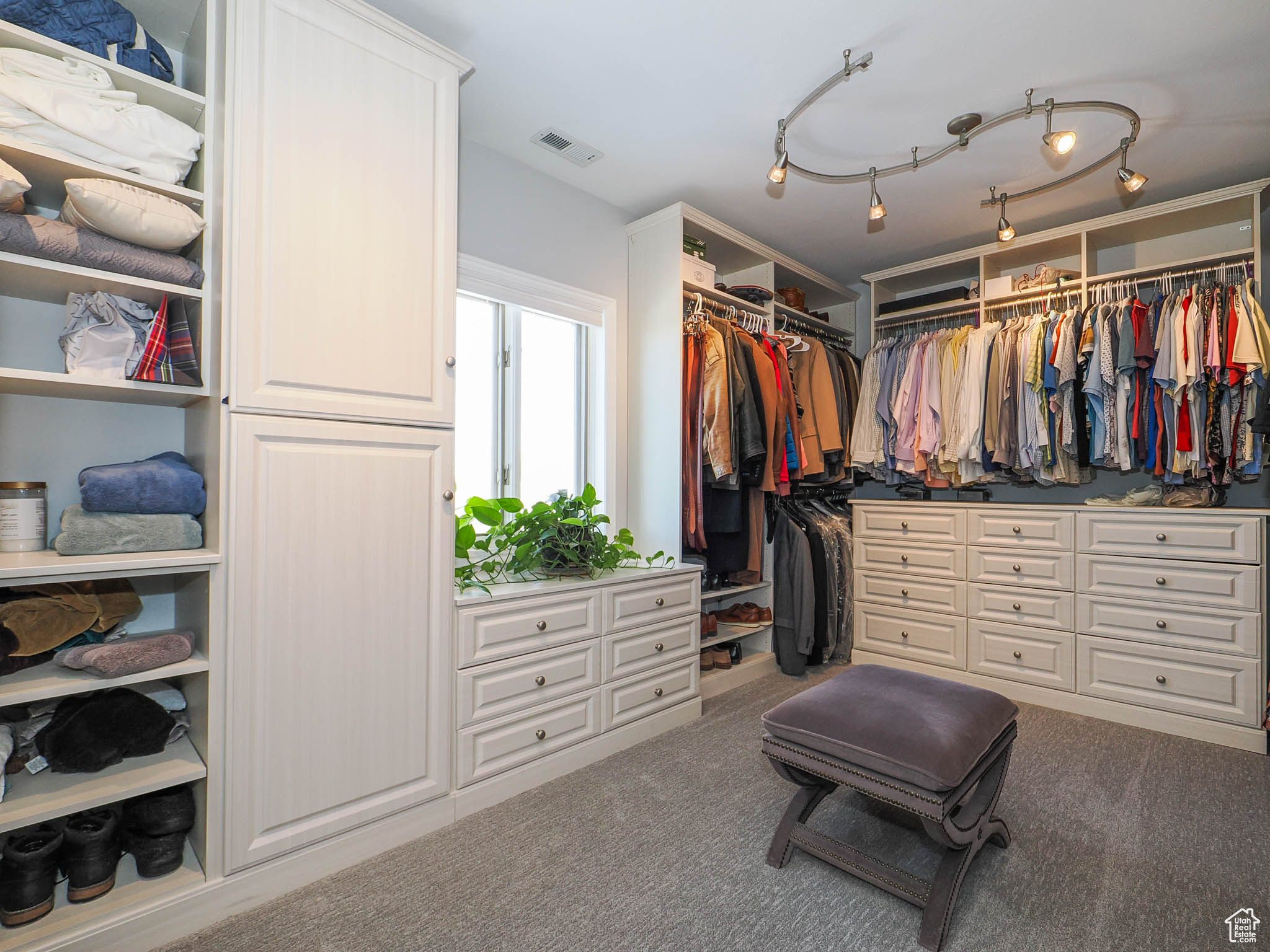 Spacious walk-in closet with built-in cabinetry and large window