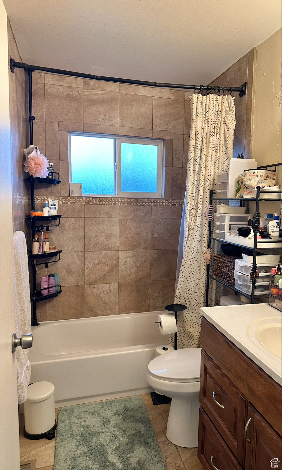 Full bathroom featuring toilet, vanity, tile floors, shower / bath combo with shower curtain, and plenty of natural light