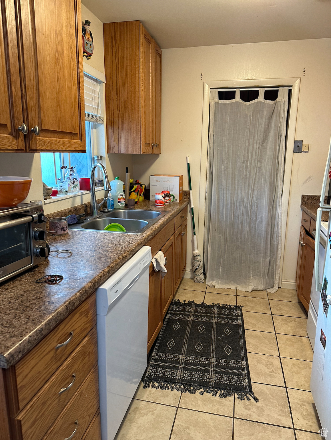 Kitchen with sink, dishwasher, and light tile floors