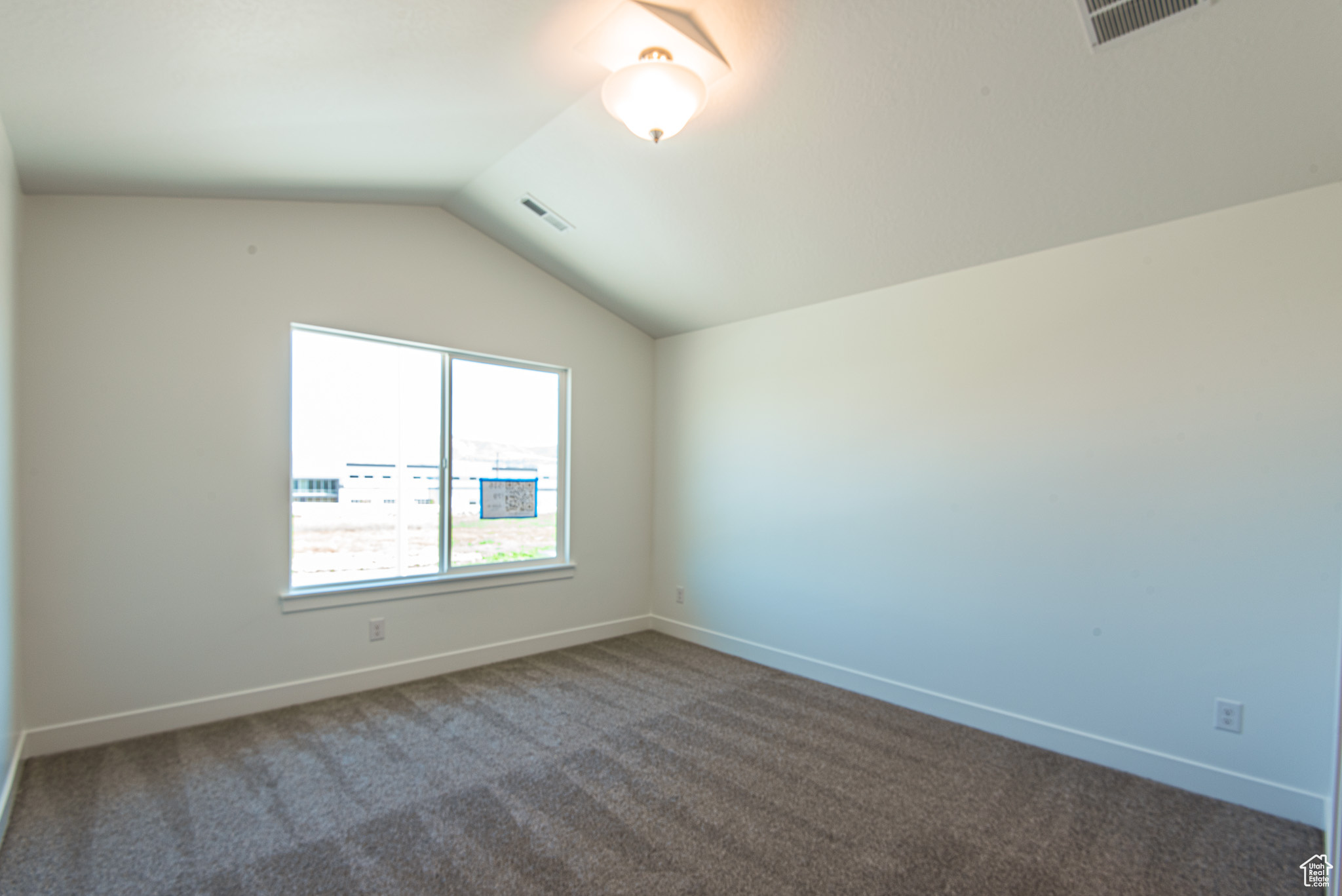 Carpeted empty room with lofted ceiling