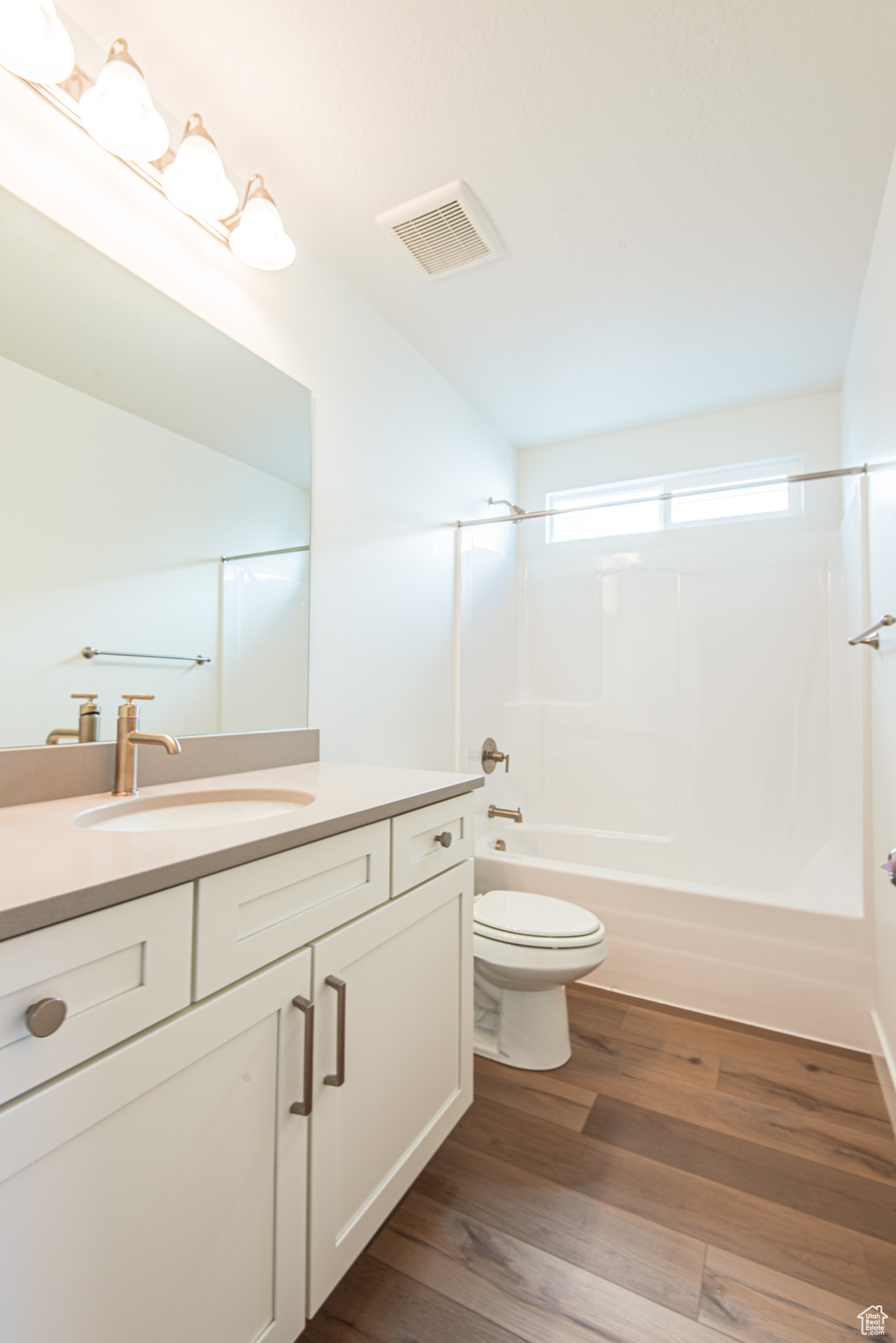 Full bathroom with wood-type flooring, vanity, toilet, and bathtub / shower combination