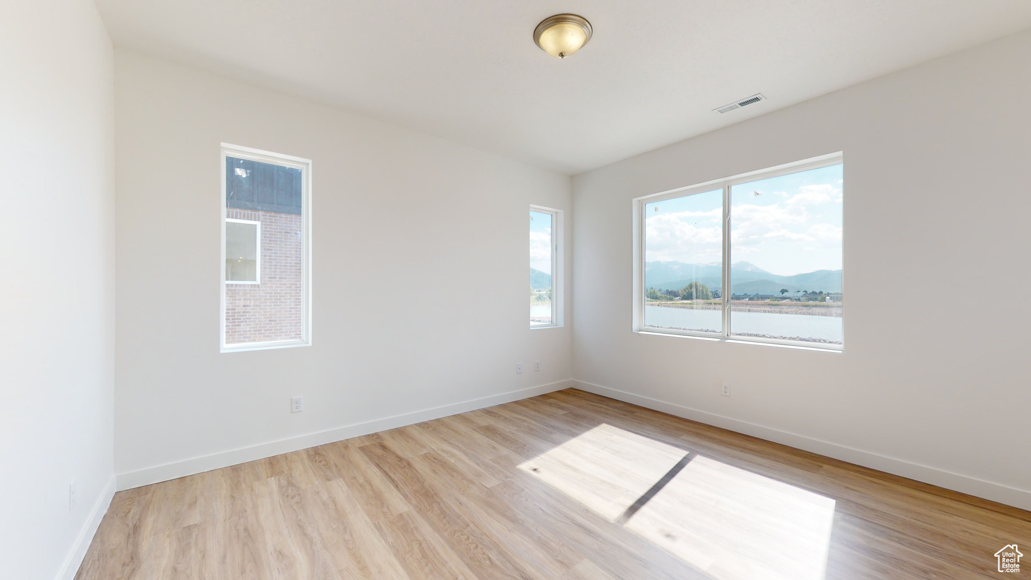 Unfurnished room with a water and mountain view and light hardwood / wood-style flooring