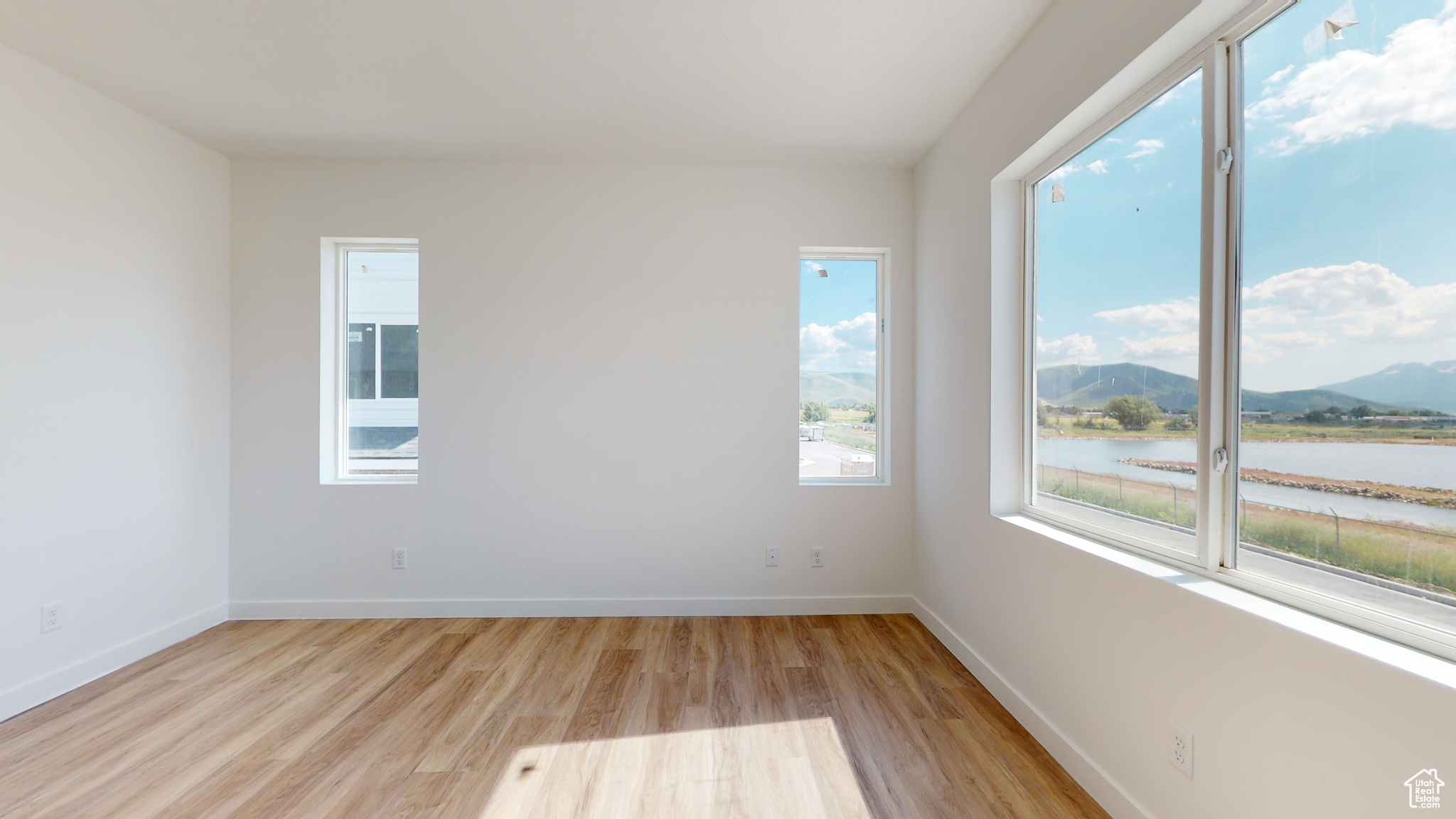 Unfurnished room with a water and mountain view and light wood-type flooring