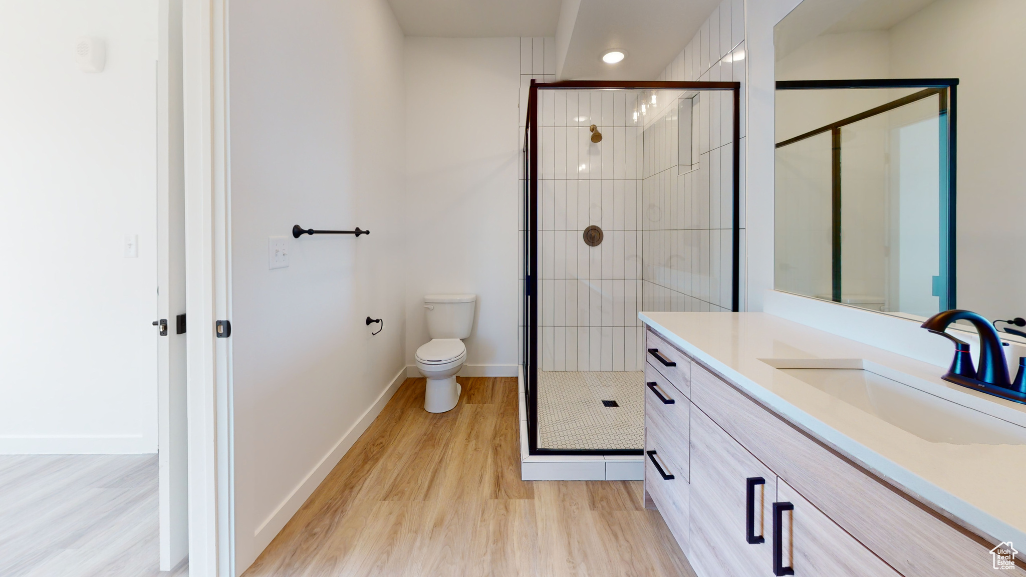 Bathroom with vanity, toilet, hardwood / wood-style floors, and an enclosed shower