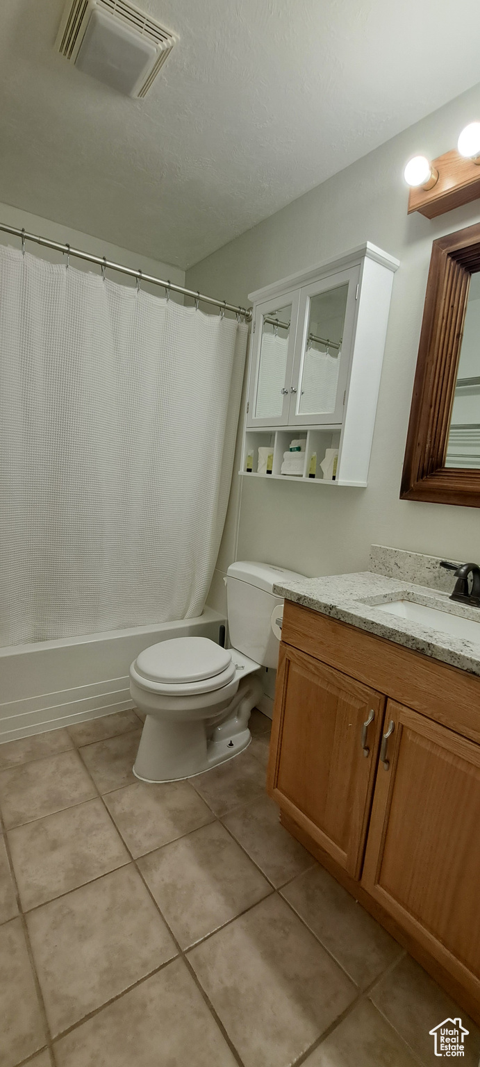 Full bathroom featuring tile floors, toilet, vanity, and shower / bath combo