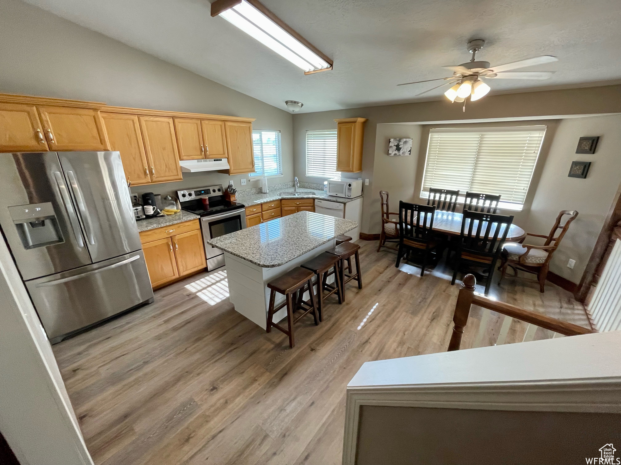 Kitchen featuring a center island, light hardwood / wood-style flooring, stainless steel appliances, ceiling fan, and lofted ceiling