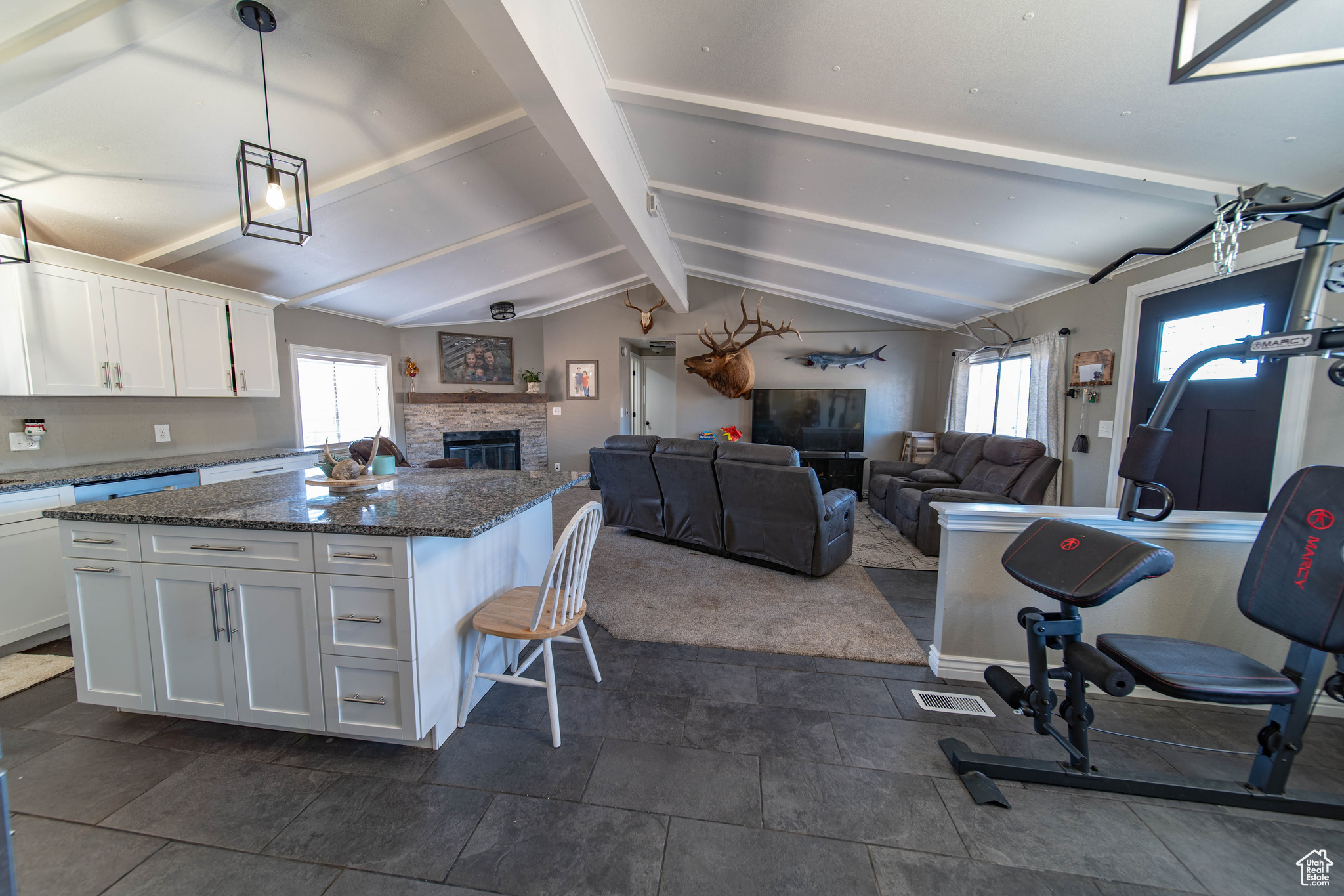 Kitchen with white cabinetry, a wealth of natural light, a fireplace, and lofted ceiling with beams