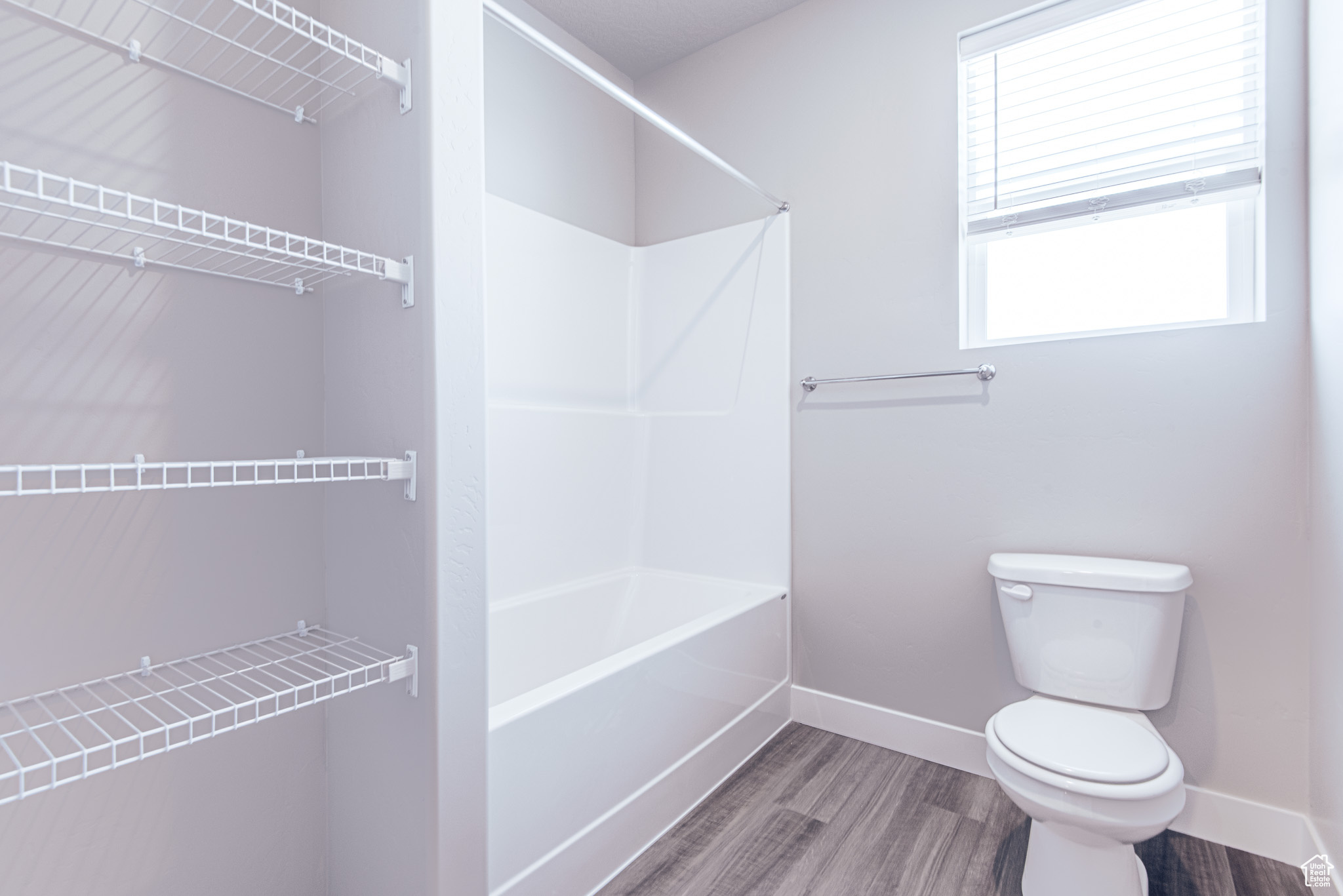 Bathroom with shower / tub combination, toilet, and hardwood / wood-style flooring