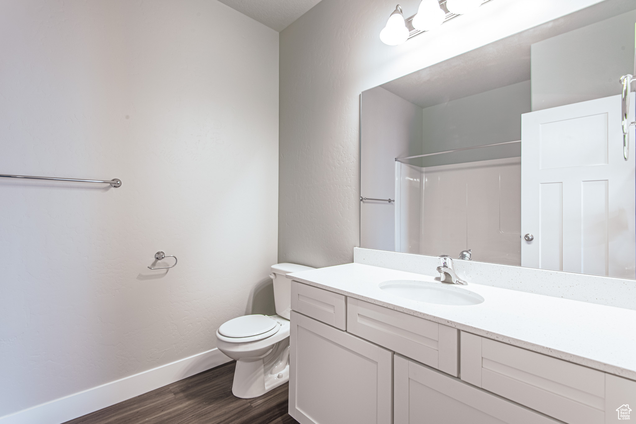 Bathroom with vanity with extensive cabinet space, toilet, and hardwood / wood-style floors