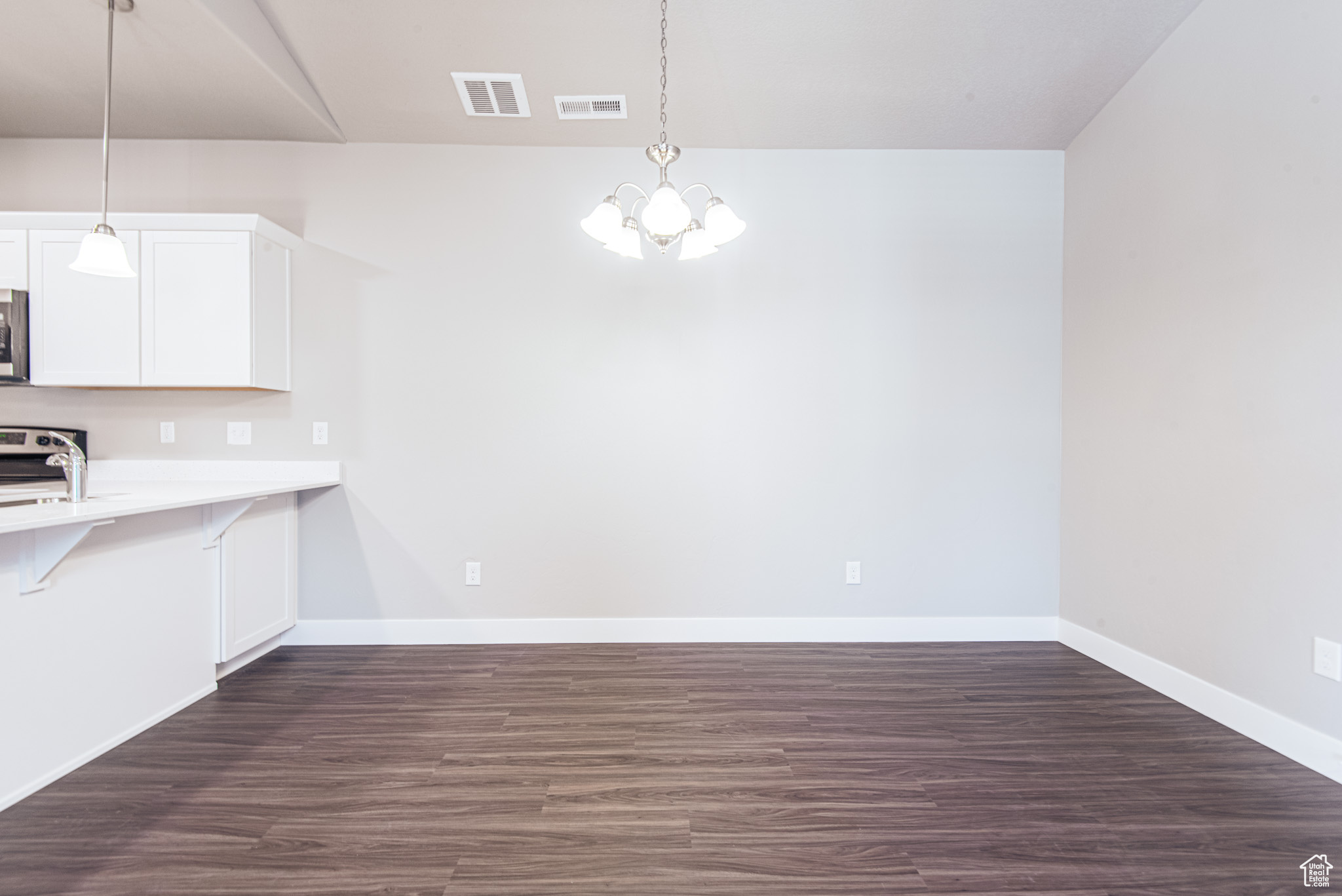 Kitchen featuring hanging light fixtures, a kitchen bar, white cabinetry, and dark hardwood / wood-style floors