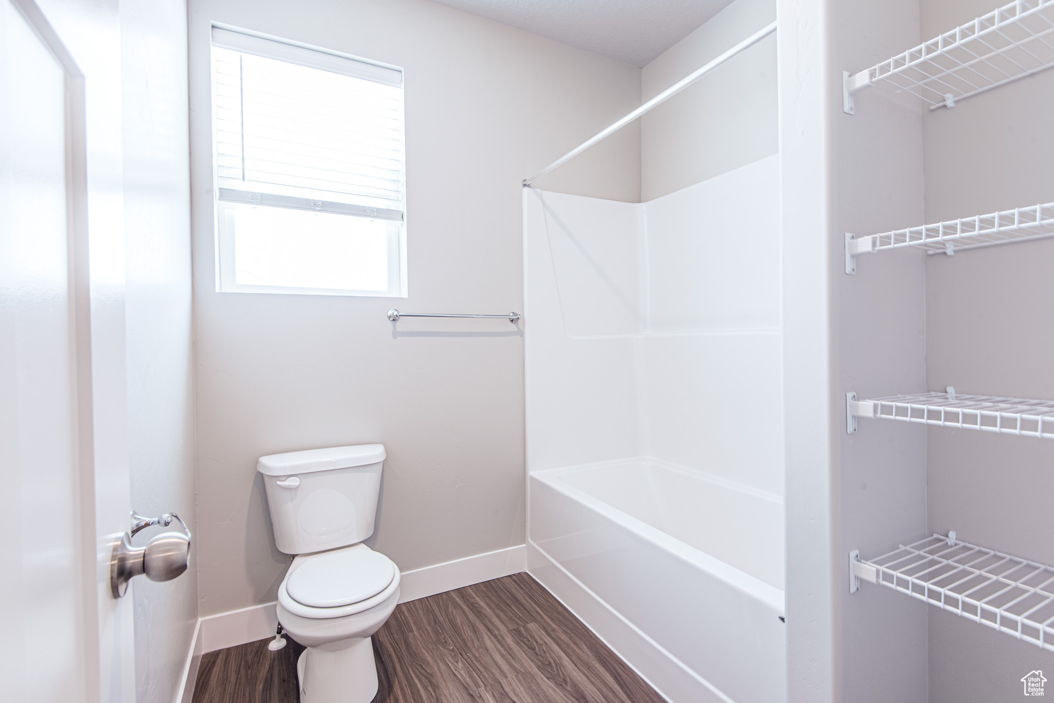 Bathroom featuring hardwood / wood-style flooring, toilet, and bathtub / shower combination