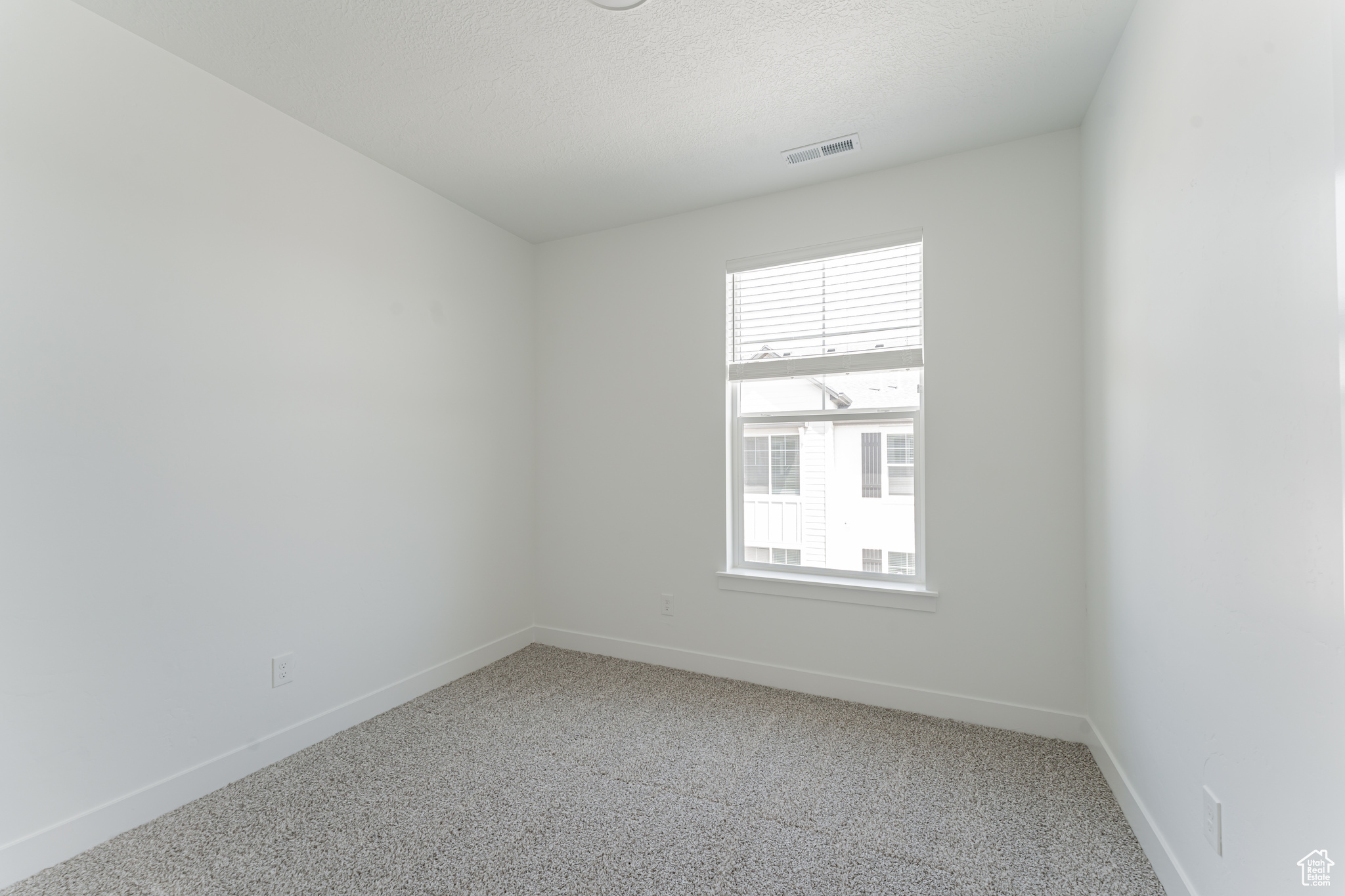 Carpeted empty room featuring a textured ceiling and plenty of natural light