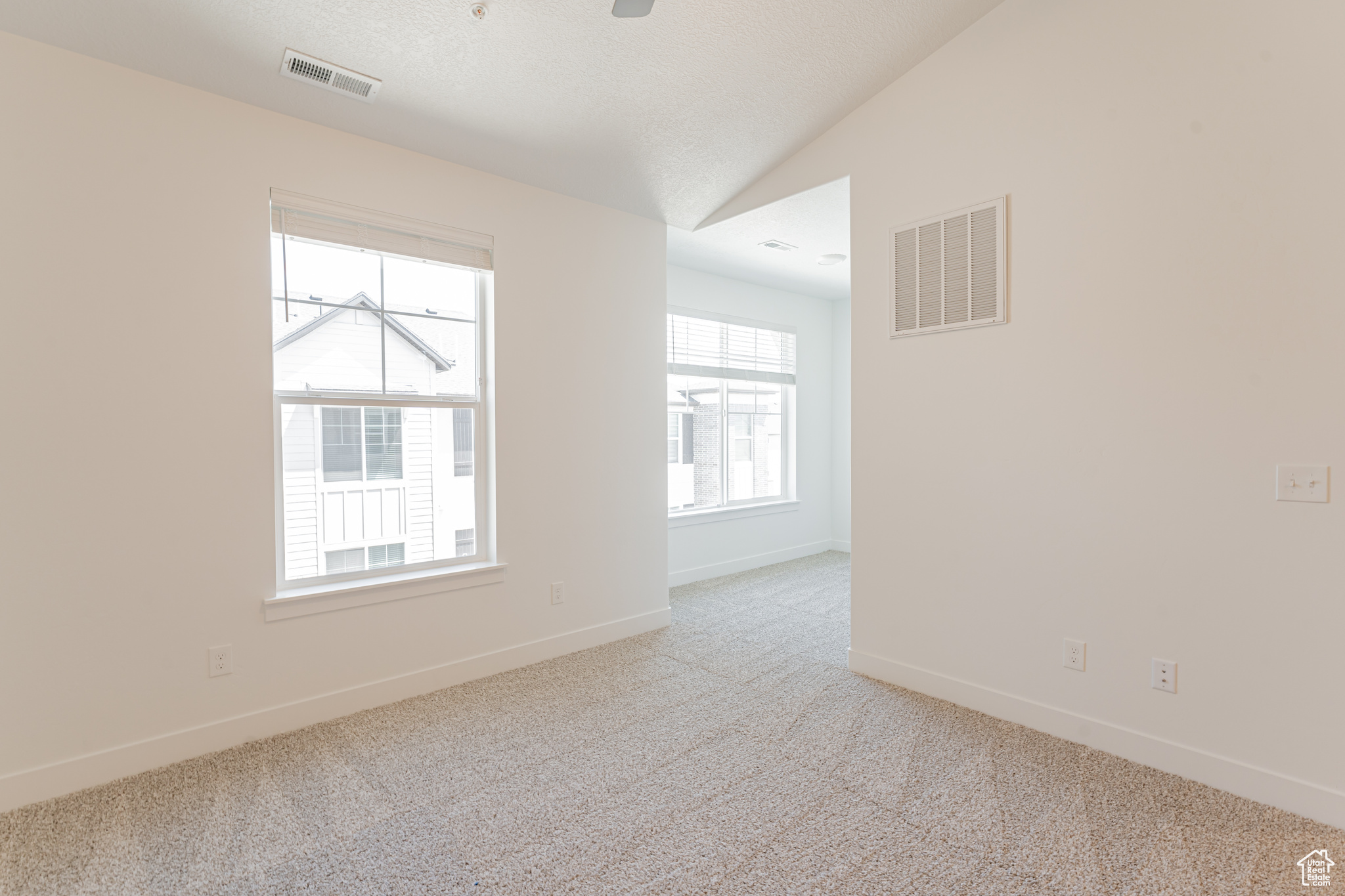 Spare room with vaulted ceiling and light colored carpet