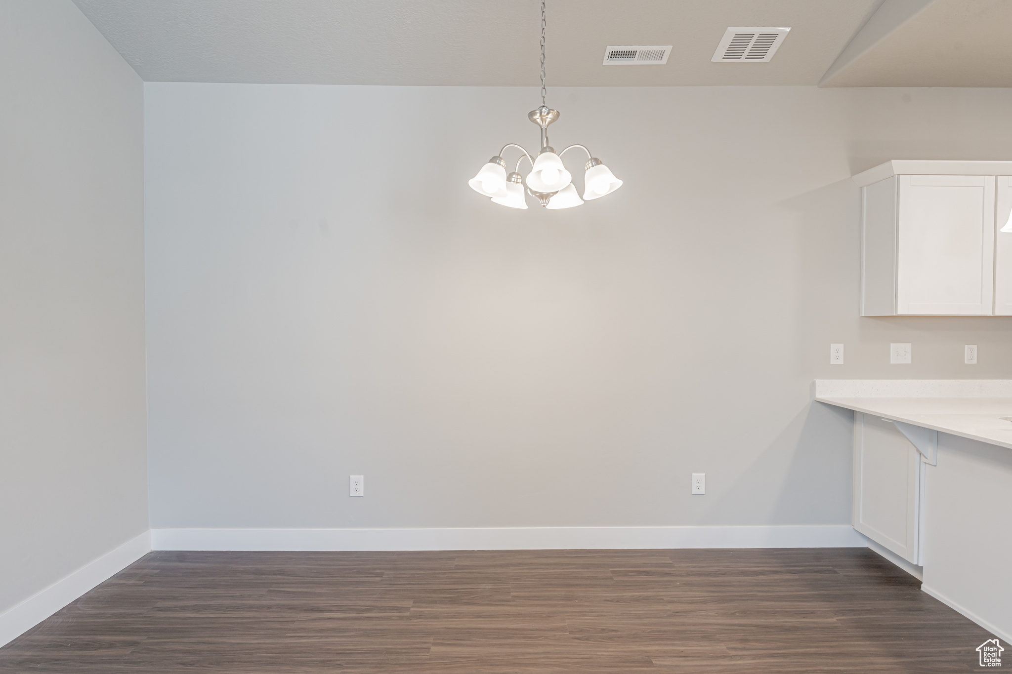 Unfurnished dining area featuring a notable chandelier and dark hardwood / wood-style flooring