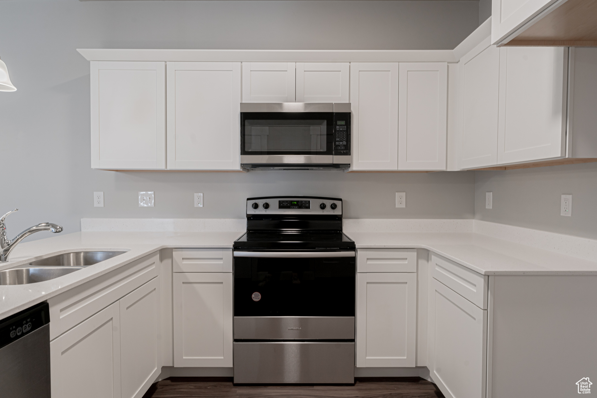 Kitchen featuring sink, dark wood-type flooring, white cabinets, and appliances with stainless steel finishes