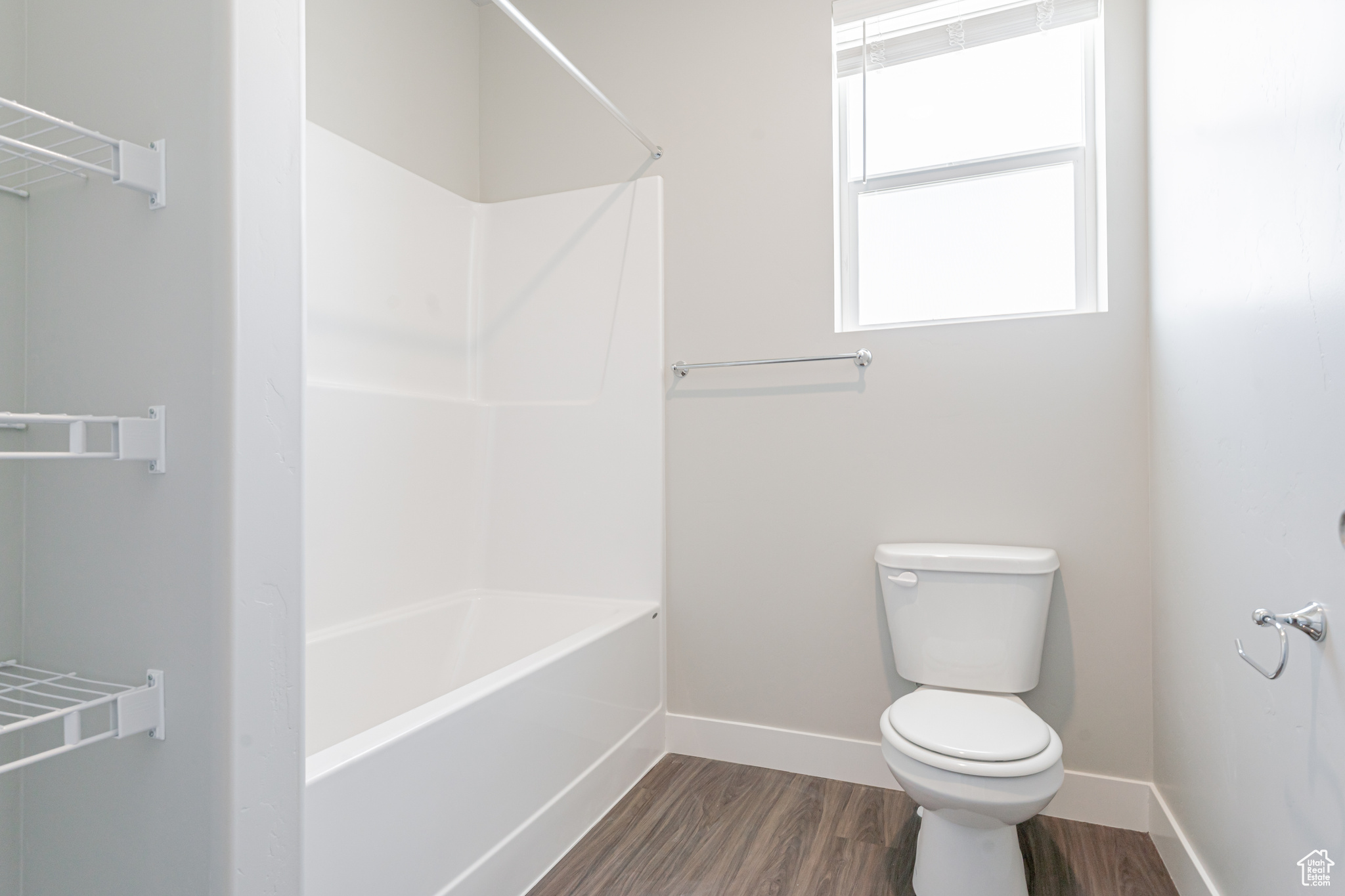 Bathroom featuring hardwood / wood-style flooring, toilet, and bathing tub / shower combination