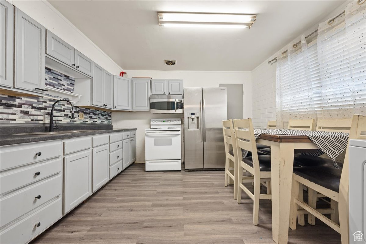 Kitchen featuring stainless steel appliances, backsplash, light hardwood / wood-style floors, sink, and gray cabinetry