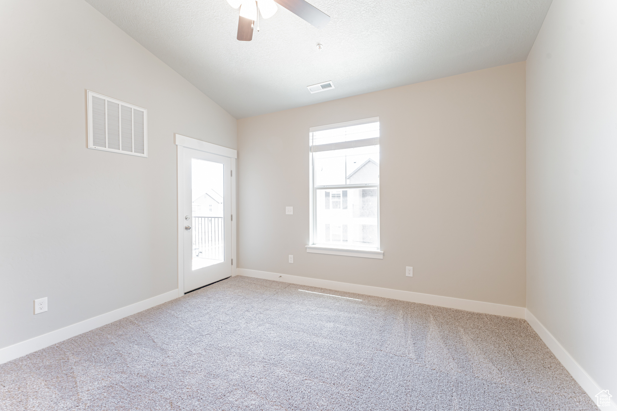 Empty room featuring light carpet, ceiling fan, and lofted ceiling