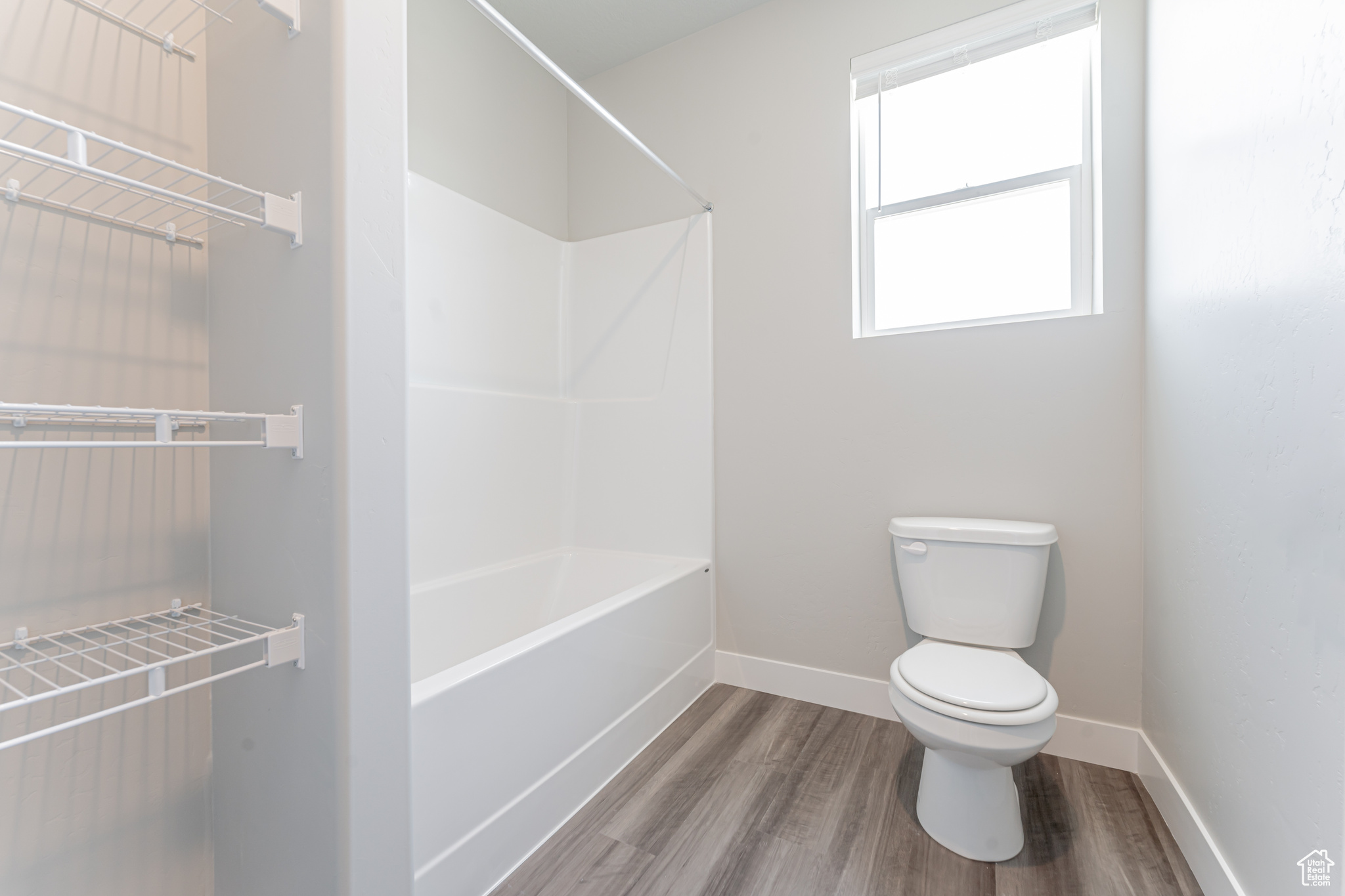 Bathroom featuring hardwood / wood-style flooring, shower / bathing tub combination, and toilet